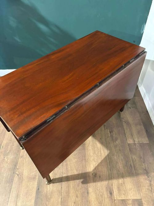 fig 5. A Victorian mahogany drop-leaf gateleg table with two extended leaves, straight legs, and small brass castors.