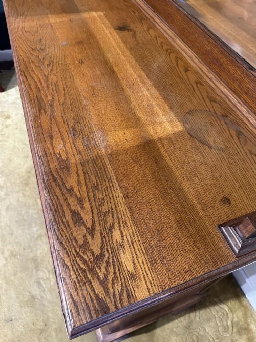 fig 6. A golden oak sideboard featuring a central mirror back flanked by two curved leaded glass cabinets above two drawers and two cupboard doors.