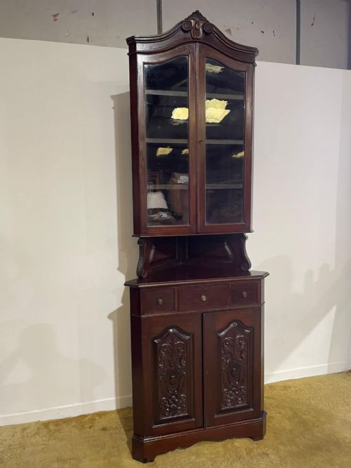 fig 2. A tall, dark mahogany late 19th-century corner cupboard featuring a glazed upper display cabinet, an open central gallery, and carved lower panel doors.