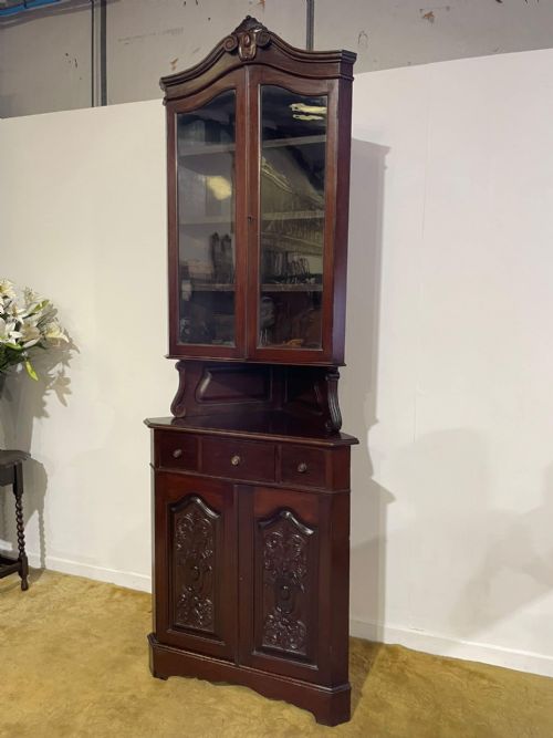 fig 4. A tall, dark mahogany late 19th-century corner cupboard featuring a glazed upper display cabinet, an open central gallery, and carved lower panel doors.