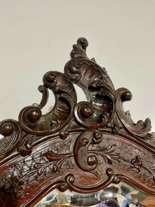fig 5. A Victorian carved mahogany frame featuring ornate cresting scrollwork, cross-hatch detailing, and a shaped bevelled glass mirror plate.