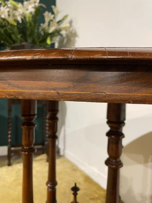 fig 5. Victorian oval burr walnut occasional table featuring four turned column supports, a central finial, and carved legs on castors.