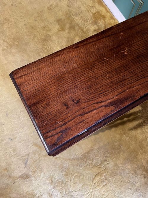 fig 5. A dark brown oak drop-leaf table with folded side flaps standing on six barley twist legs connected by lower stretchers.