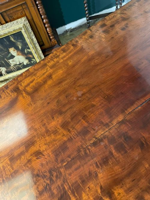 fig 6. A late Regency mahogany tilt-top breakfast table featuring a rectangular polished top with rounded corners, supported by a central pedestal and reeded quadruped legs with brass paw feet.