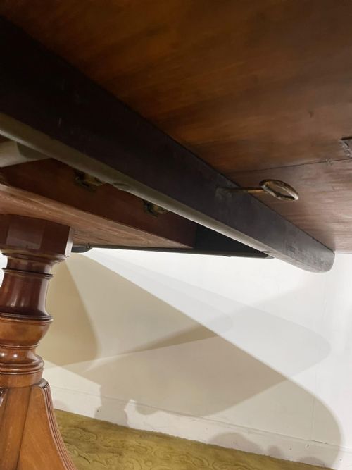fig 7. A late Regency mahogany tilt-top breakfast table featuring a rectangular polished top with rounded corners, supported by a central pedestal and reeded quadruped legs with brass paw feet.