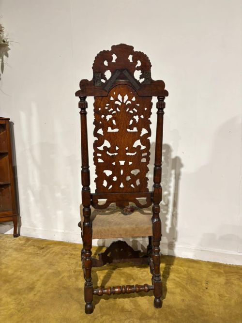 fig 7. A Carolean carved oak high back side chair featuring an intricately carved foliage cresting, turned supports, and a floral needlepoint seat.