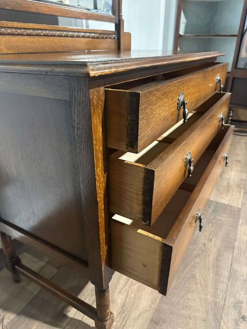 fig 1. A vintage oak dressing table with three long drawers, drop handles, turned legs, and an attached pivoting mirror.