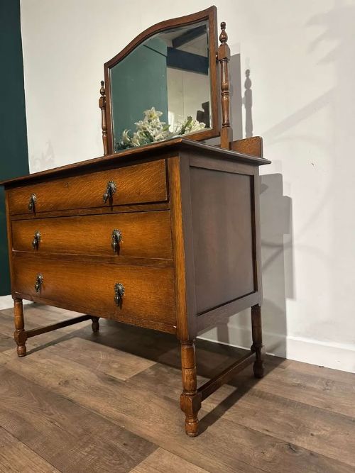fig 3. A vintage oak dressing table with three long drawers, drop handles, turned legs, and an attached pivoting mirror.
