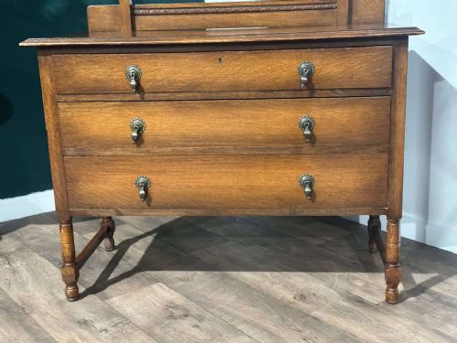 fig 4. A vintage oak dressing table with three long drawers, drop handles, turned legs, and an attached pivoting mirror.