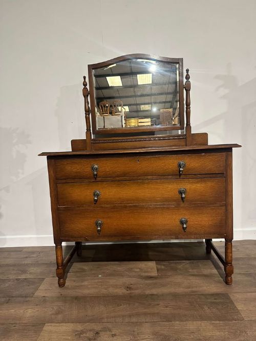 fig 6. A vintage oak dressing table with three long drawers, drop handles, turned legs, and an attached pivoting mirror.