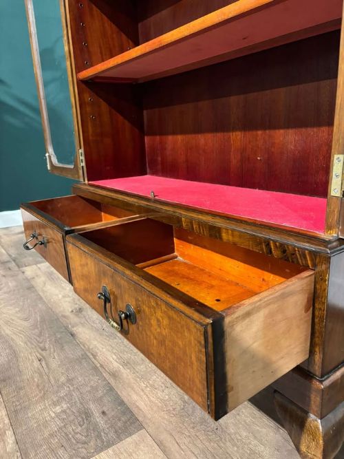 fig 5. A 1930s walnut display cabinet featuring two glazed doors with arched upper panels, red fabric-lined shelves, two lower drawers, and cabriole legs.