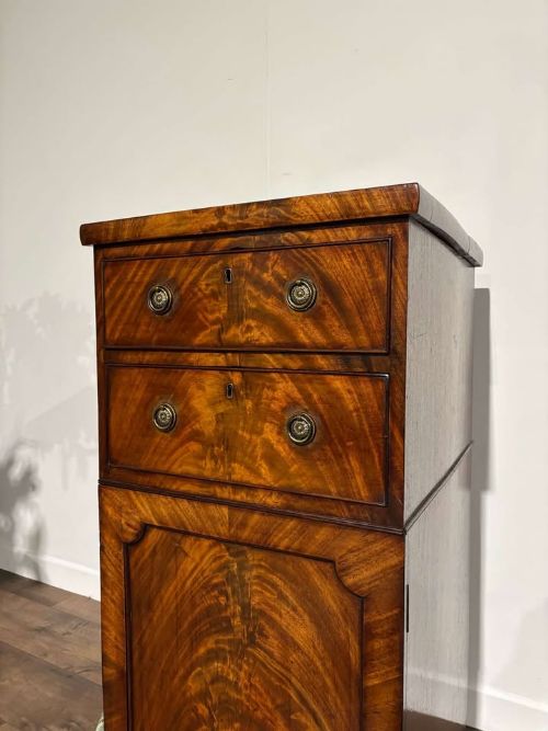 fig 3. A tall Victorian flame mahogany cabinet featuring two upper drawers with brass ring handles above a single panelled cupboard door on a plinth base.
