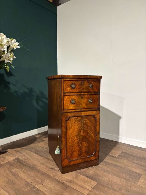 fig 5. A tall Victorian flame mahogany cabinet featuring two upper drawers with brass ring handles above a single panelled cupboard door on a plinth base.