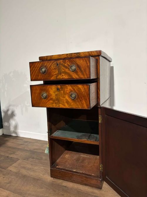 fig 8. A tall Victorian flame mahogany cabinet featuring two upper drawers with brass ring handles above a single panelled cupboard door on a plinth base.