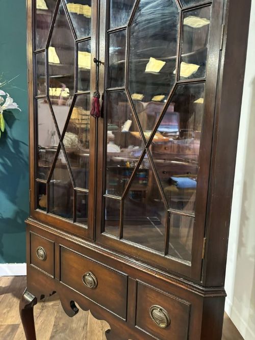 fig 4. A tall mahogany corner display cabinet featuring astragal glazed doors, a fretwork frieze, and elevated on cabriole legs.