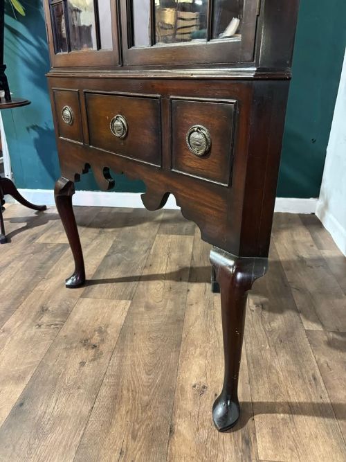fig 8. A tall mahogany corner display cabinet featuring astragal glazed doors, a fretwork frieze, and elevated on cabriole legs.