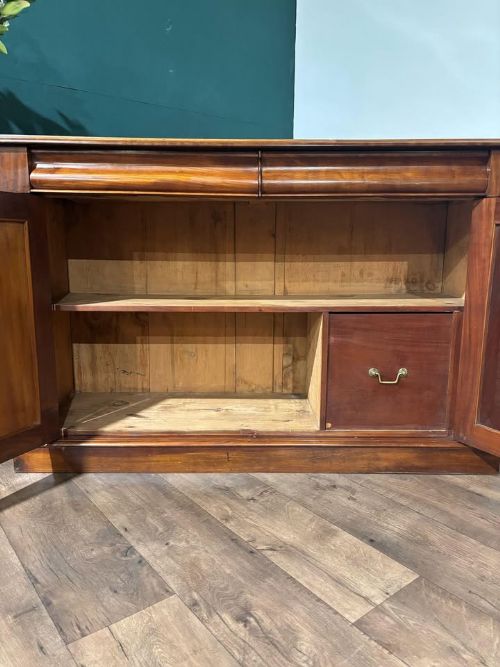 fig 8. A Victorian mahogany chiffonier featuring two flame-veneered door panels flanked by carved corbels, set beneath a frieze drawer and resting on a plinth base.
