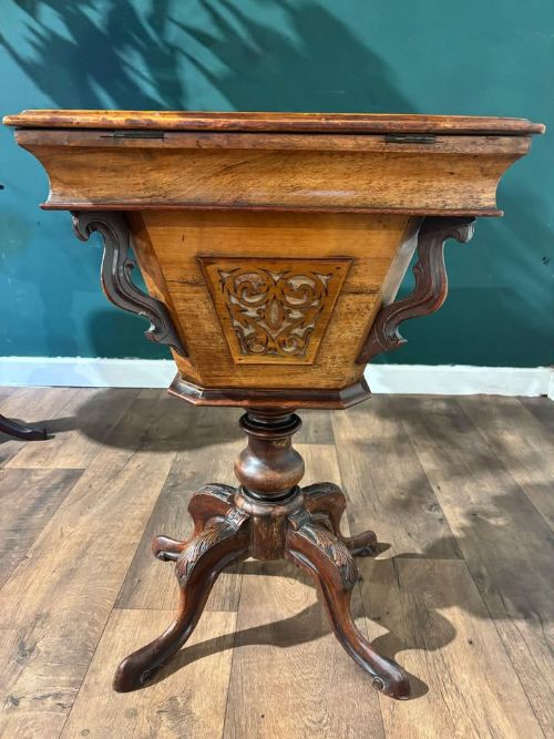 fig 1. A 19th-century Victorian walnut trumpet sewing table with fretwork side panels, a hinged top lid, turned pedestal, and carved tripod cabriole legs.