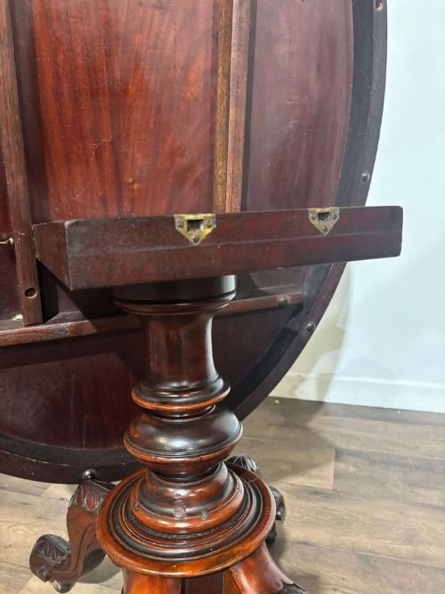 fig 2. An oval Victorian mahogany breakfast table featuring a central turned pedestal and four carved legs with castors.