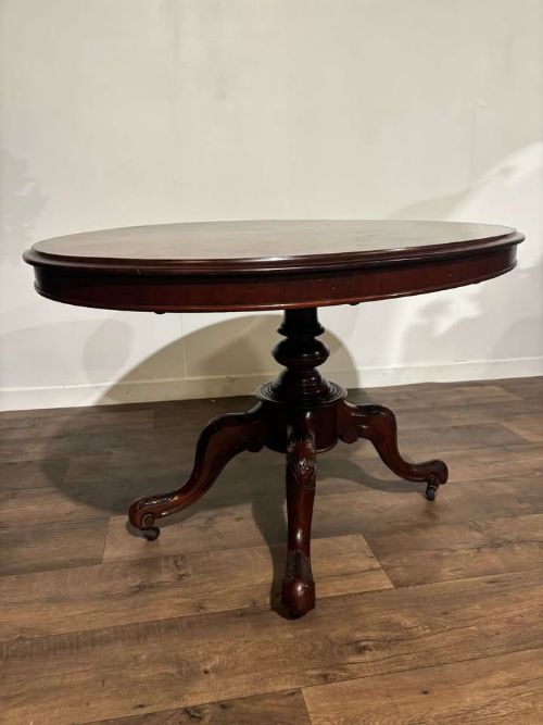 fig 3. An oval Victorian mahogany breakfast table featuring a central turned pedestal and four carved legs with castors.