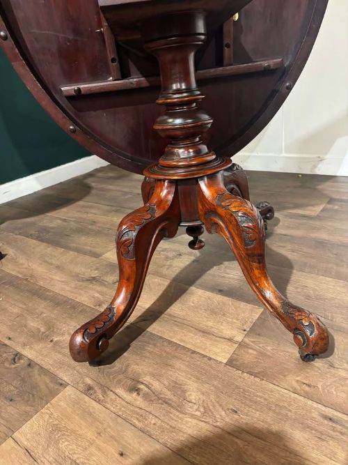 fig 4. An oval Victorian mahogany breakfast table featuring a central turned pedestal and four carved legs with castors.