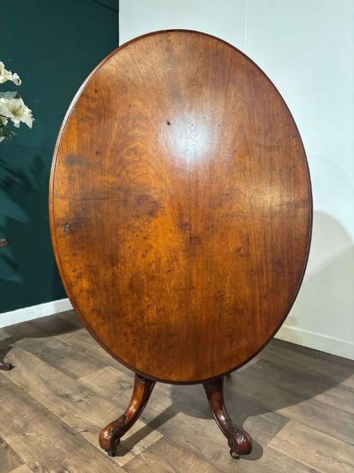 fig 5. An oval Victorian mahogany breakfast table featuring a central turned pedestal and four carved legs with castors.