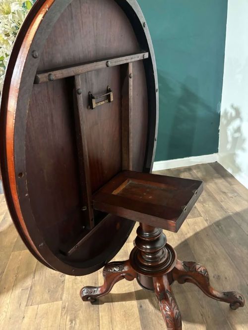 fig 6. An oval Victorian mahogany breakfast table featuring a central turned pedestal and four carved legs with castors.