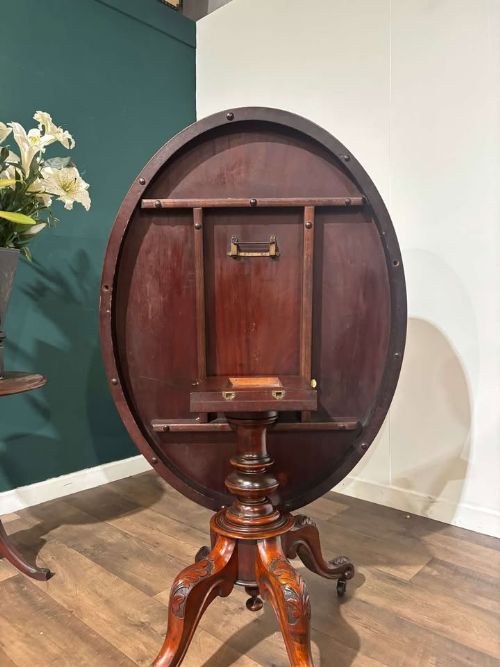 fig 8. An oval Victorian mahogany breakfast table featuring a central turned pedestal and four carved legs with castors.
