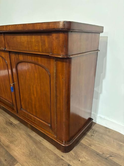 fig 5. A Victorian flame mahogany chiffonier featuring two frieze drawers set over two arched panelled cupboard doors resting on a solid plinth base.