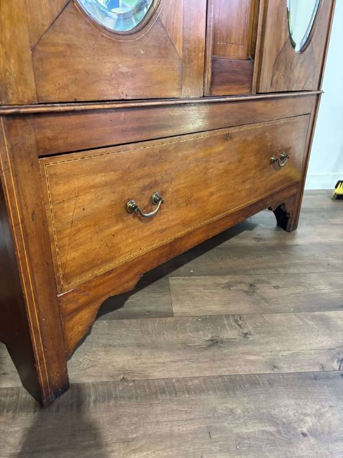 fig 1. An Edwardian walnut double wardrobe featuring two full-length oval mirrored doors flanking an inlaid central panel above a wide base drawer.
