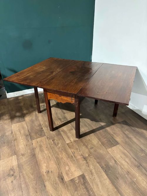 fig 7. An antique Georgian dark mahogany drop-leaf table shown standing fully extended on straight moulded legs.