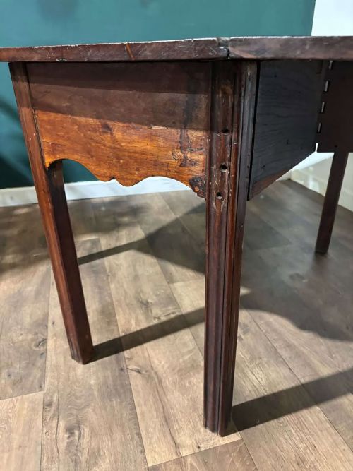 fig 9. An antique Georgian dark mahogany drop-leaf table shown standing fully extended on straight moulded legs.
