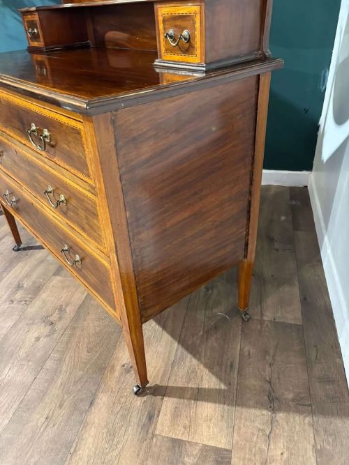 fig 5. An Edwardian mahogany dressing table featuring three long drawers with crossbanded inlay, two small upper jewellery drawers, tapered legs on castors, and a large oval swivel mirror.