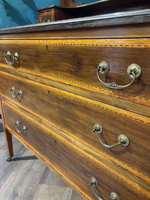 fig 9. An Edwardian mahogany dressing table featuring three long drawers with crossbanded inlay, two small upper jewellery drawers, tapered legs on castors, and a large oval swivel mirror.
