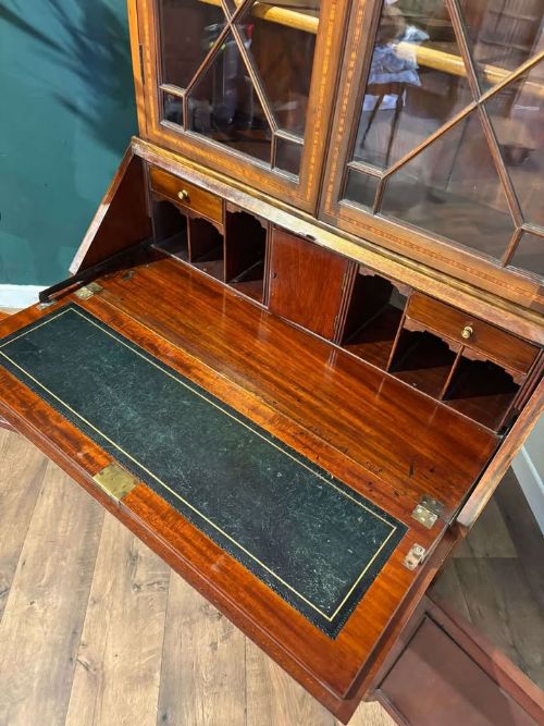 fig 2. An Edwardian inlaid mahogany bureau bookcase featuring upper geometric glazed doors above a slant-front drop-down desk and lower cupboards.