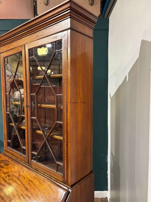 fig 3. An Edwardian inlaid mahogany bureau bookcase featuring upper geometric glazed doors above a slant-front drop-down desk and lower cupboards.