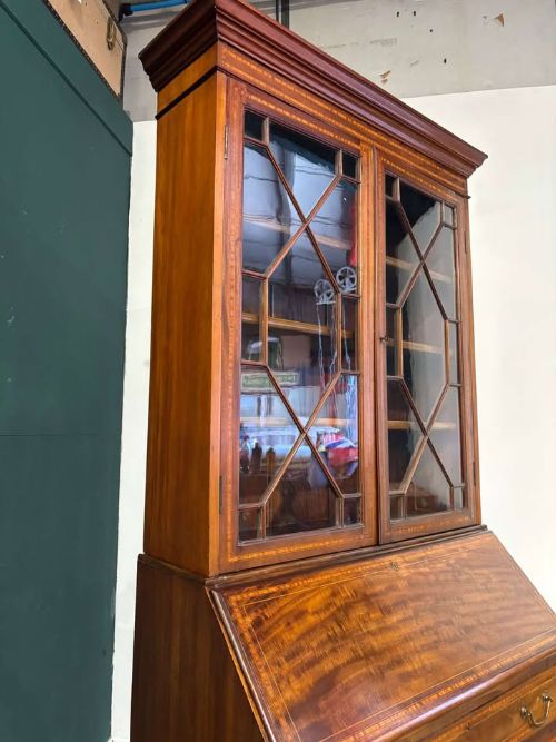 fig 4. An Edwardian inlaid mahogany bureau bookcase featuring upper geometric glazed doors above a slant-front drop-down desk and lower cupboards.