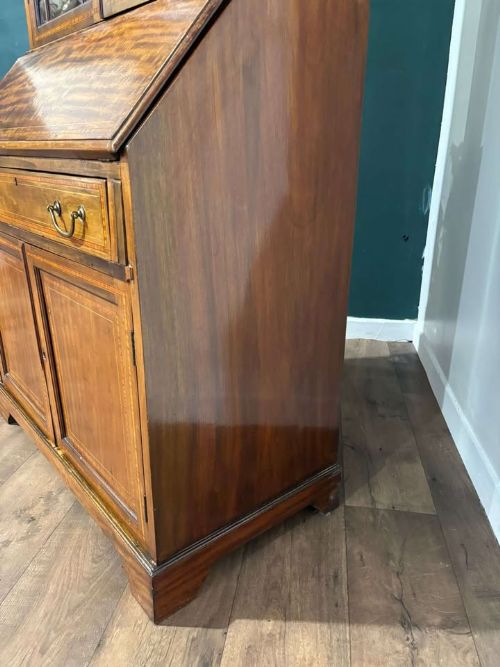 fig 5. An Edwardian inlaid mahogany bureau bookcase featuring upper geometric glazed doors above a slant-front drop-down desk and lower cupboards.
