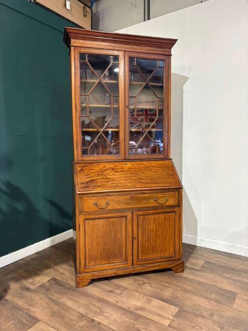 fig 6. An Edwardian inlaid mahogany bureau bookcase featuring upper geometric glazed doors above a slant-front drop-down desk and lower cupboards.
