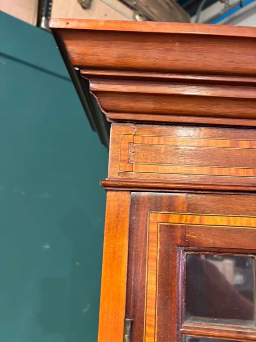 fig 7. An Edwardian inlaid mahogany bureau bookcase featuring upper geometric glazed doors above a slant-front drop-down desk and lower cupboards.