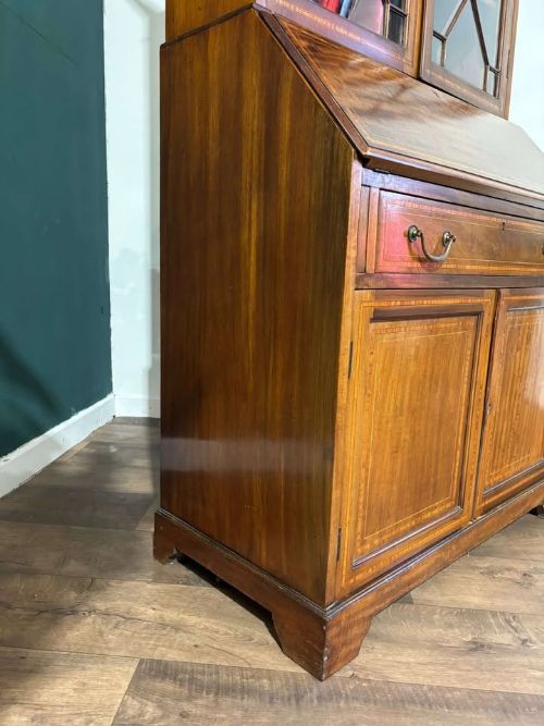 fig 8. An Edwardian inlaid mahogany bureau bookcase featuring upper geometric glazed doors above a slant-front drop-down desk and lower cupboards.