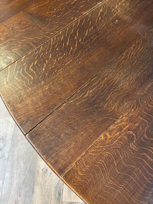 fig 5. A dark oak drop-leaf dining table with an oval top, turned legs, shaped aprons, and perimeter stretchers.