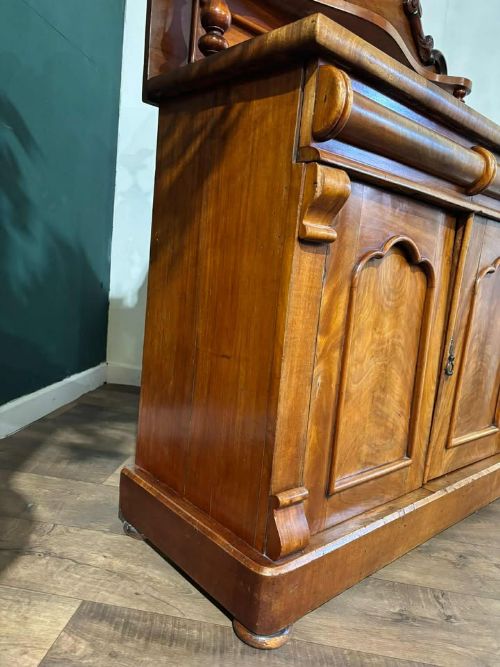 fig 1. A Victorian mahogany chiffonier cabinet featuring a scroll-carved splashback shelf over a two-door cupboard set on a solid plinth base.
