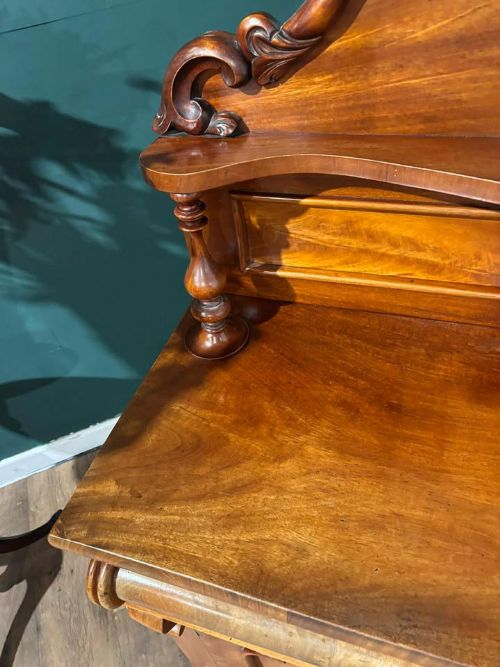 fig 2. A Victorian mahogany chiffonier cabinet featuring a scroll-carved splashback shelf over a two-door cupboard set on a solid plinth base.