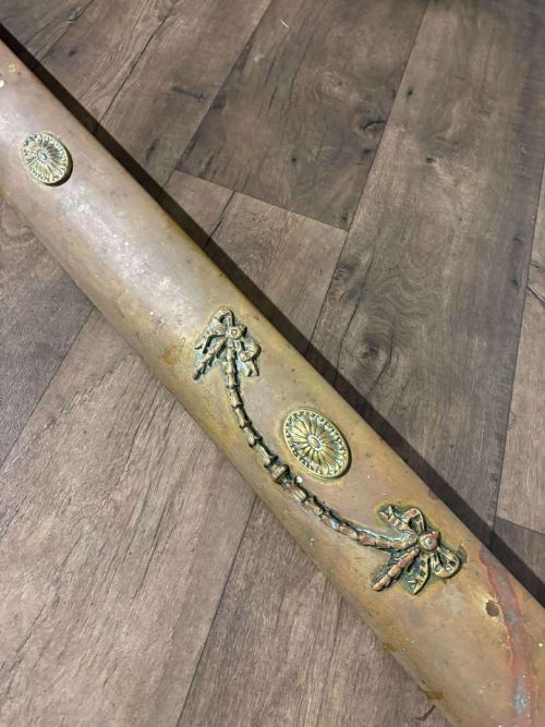 fig 2. An Edwardian brass fireplace fender featuring neoclassical swag decorative motifs on an angled metal frame.