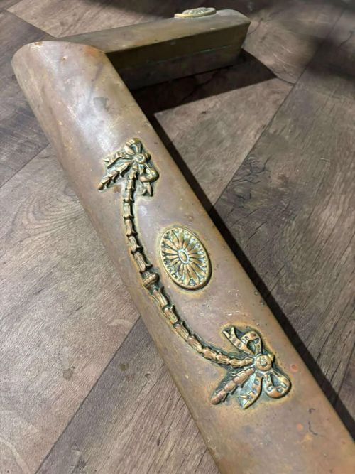 fig 5. An Edwardian brass fireplace fender featuring neoclassical swag decorative motifs on an angled metal frame.
