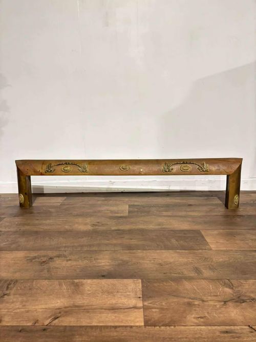 fig 6. An Edwardian brass fireplace fender featuring neoclassical swag decorative motifs on an angled metal frame.