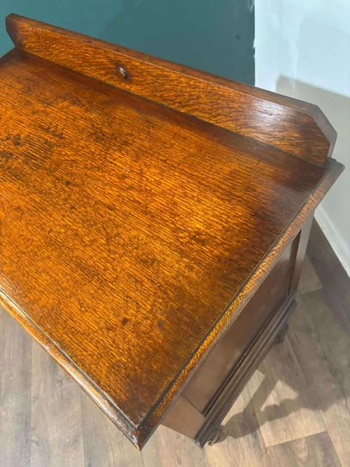 fig 8. A medium brown vintage oak chest of drawers featuring three split-panel drawer fronts, carved frieze detailing, a low back gallery, and barley twist legs connected by stretchers.