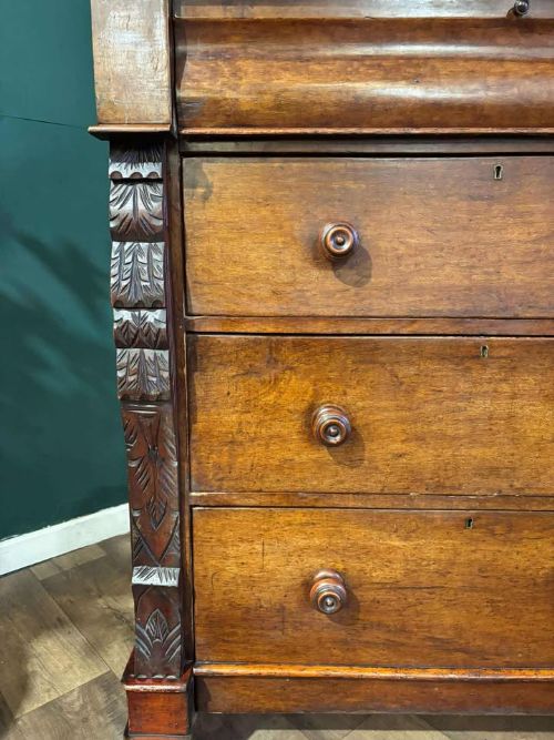 fig 8. A Victorian mahogany chest of drawers featuring carved pilasters, three main drawers with turned wooden handles, a coved top drawer, and bun feet.