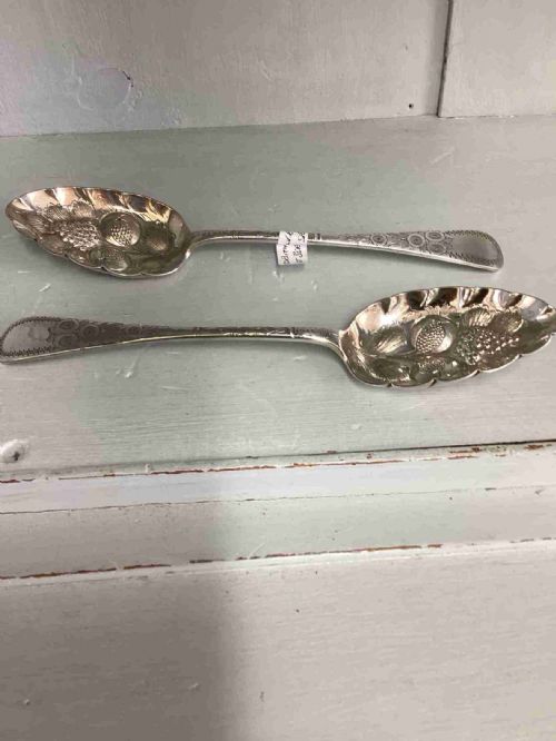 A well decorated pair of silver plated berry serving fruit spoons